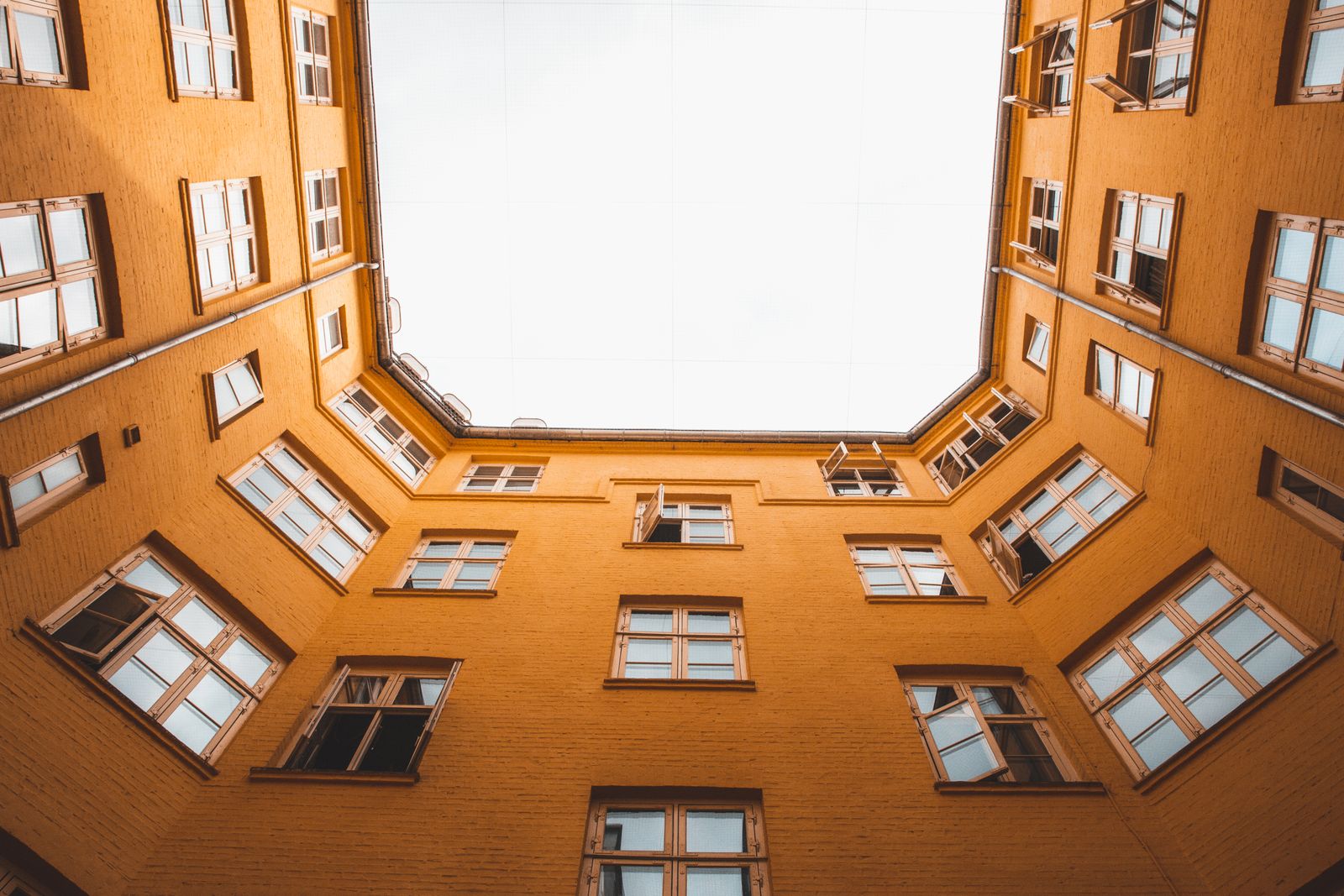 Facade på en ældre etageejendom i gule sten, set nedefra